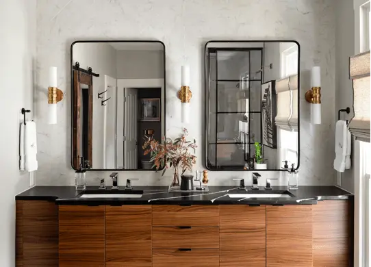 Mirrors over a double sink. The mirrors have a curved edge with black accents.