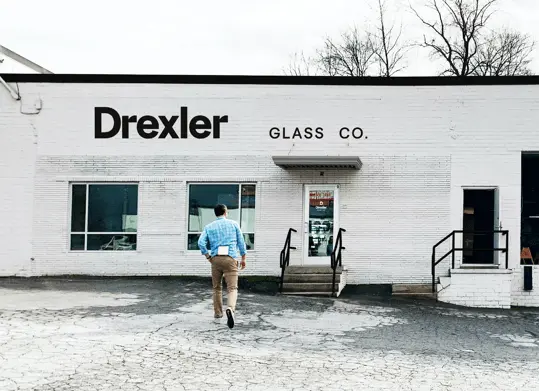 Man walking into the Drexler Glass Building