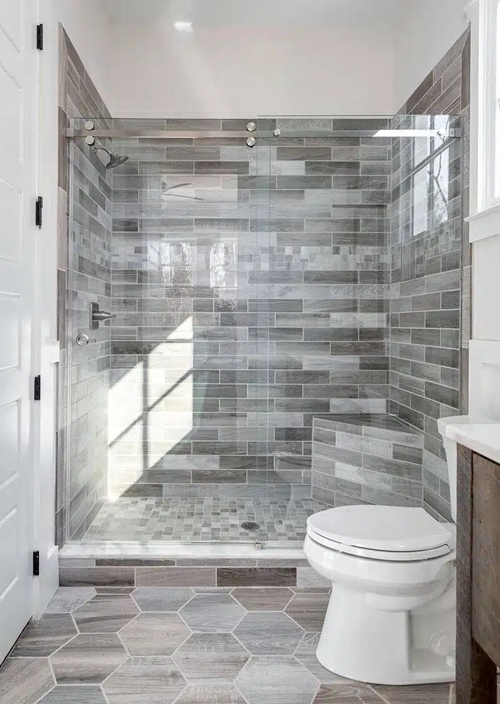 Barn door glass shower enclosure for a small shower.