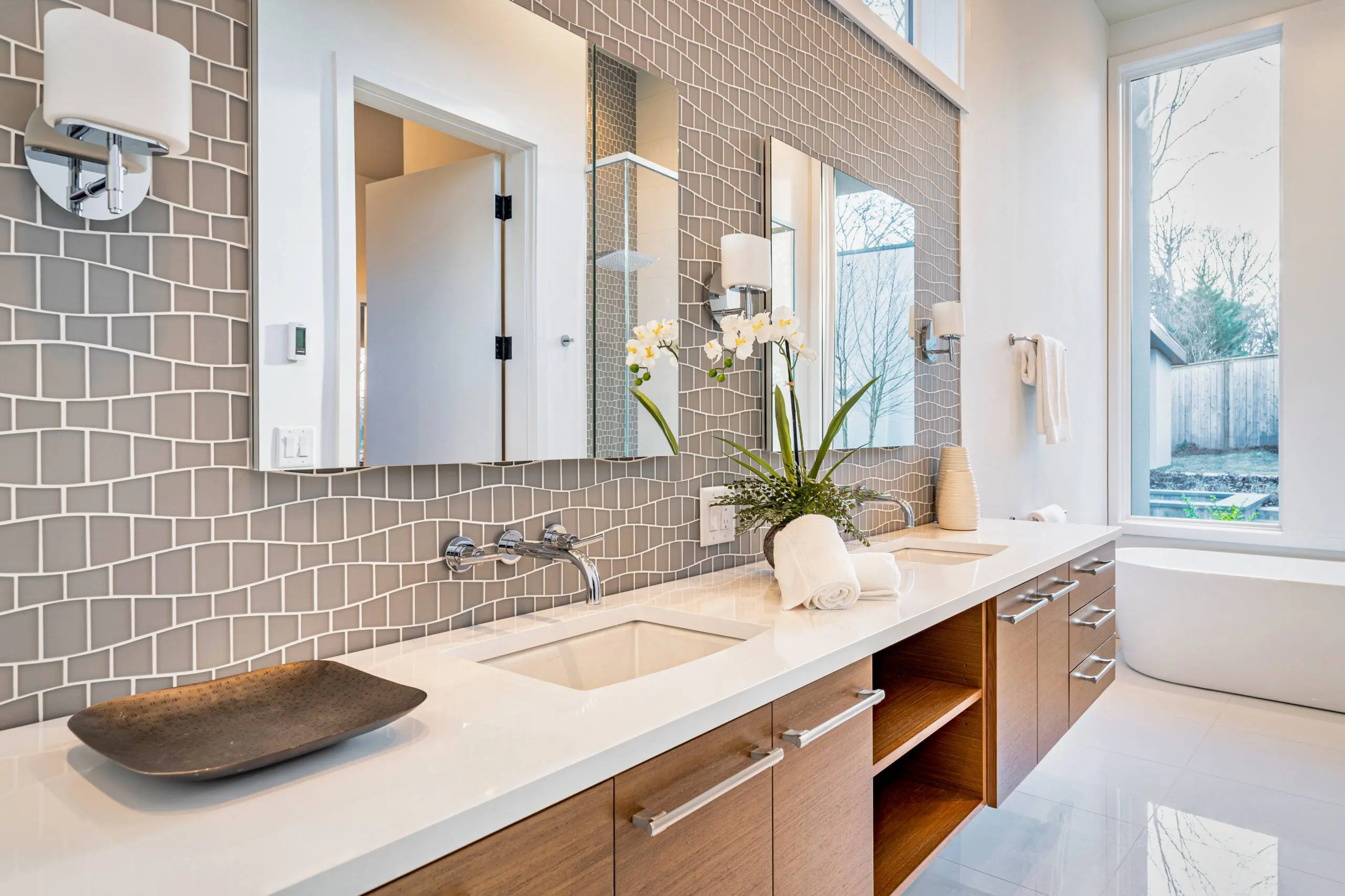 double sink bathroom with glass backsplash and two mirrors. This has a clean and simple look.