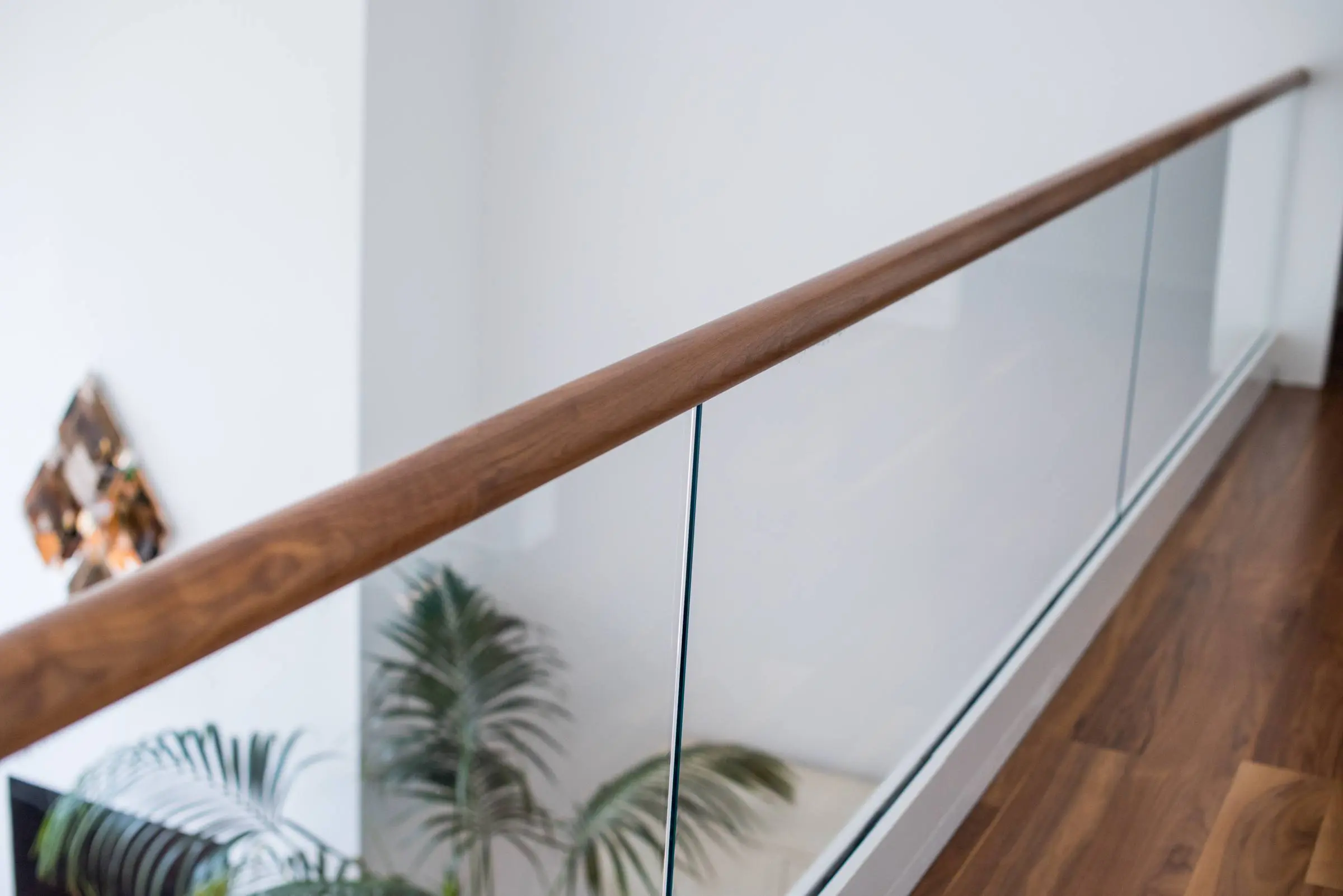 Glass railing for a balcony area with wood accent hand rails.