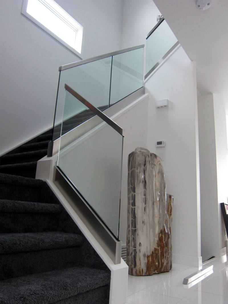 Narrow stairwell in a home with glass railing to give a more open feeling. It also includes a hand rail.